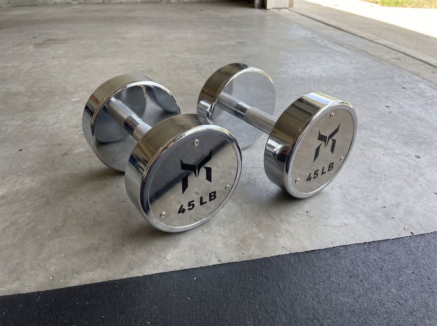 A pair of polished chrome 45 lb dumbbells on a concrete garage floor