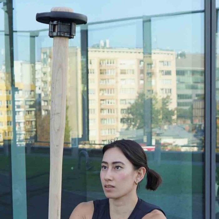 A woman in a squat holding a Kensui EZ-MACE PRO upright at an outdoor gym