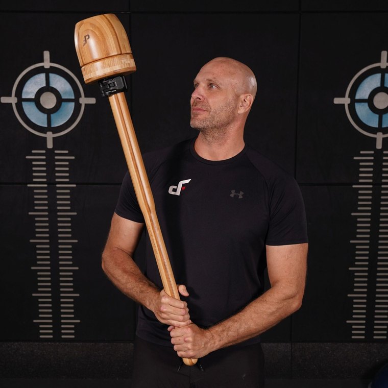 A man holding an Adjustable Maverick Mace Classic with a bamboo shaft and wooden head across his body