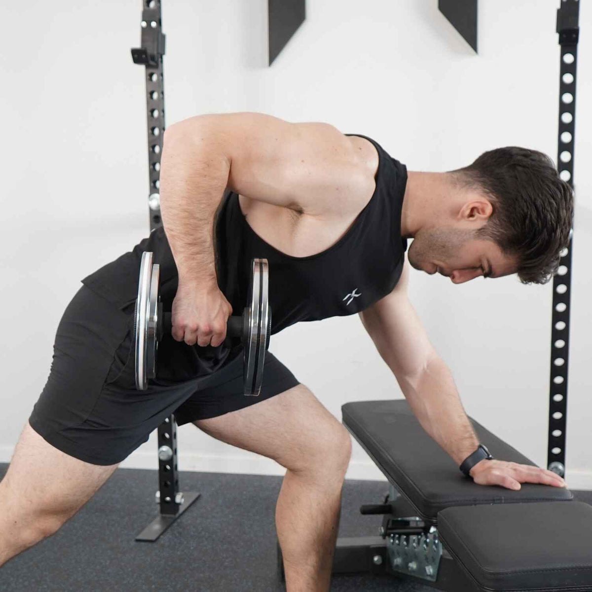 A lifter performing a one arm row with a Kensui AdaptaBELL handle loaded with chrome plates