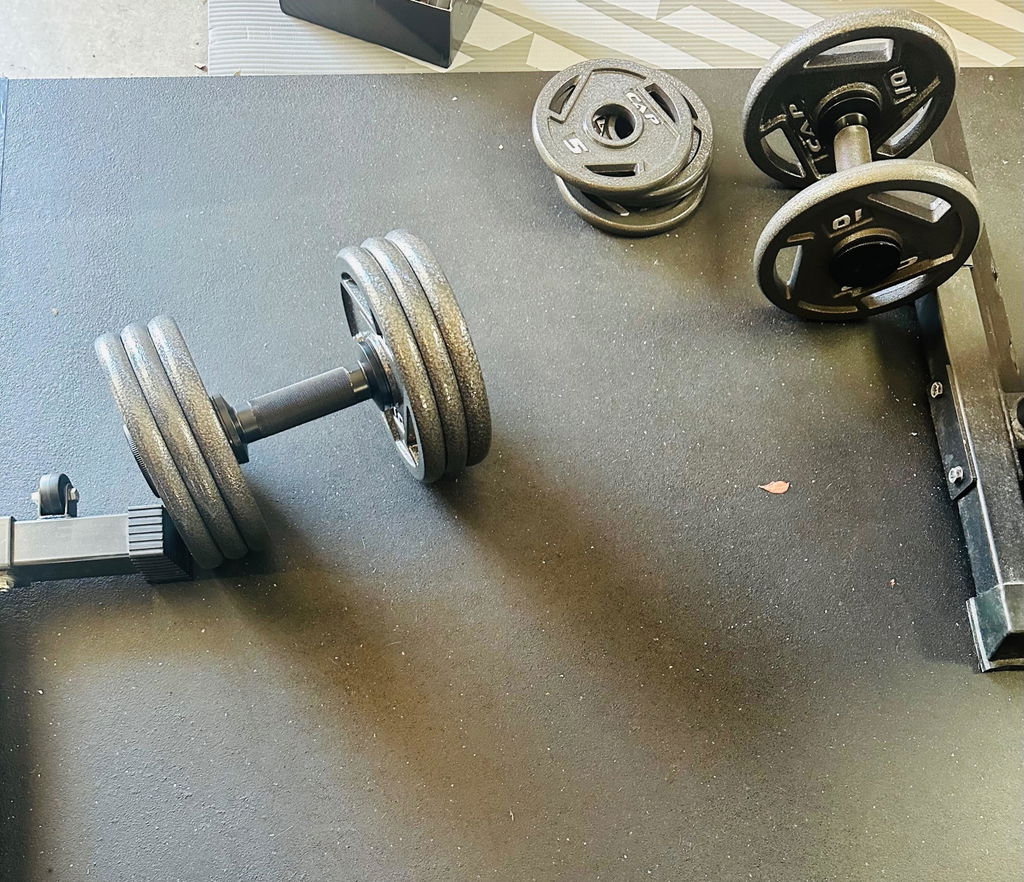 Adjustable dumbbell handle loaded beside spare plates on a gym floor