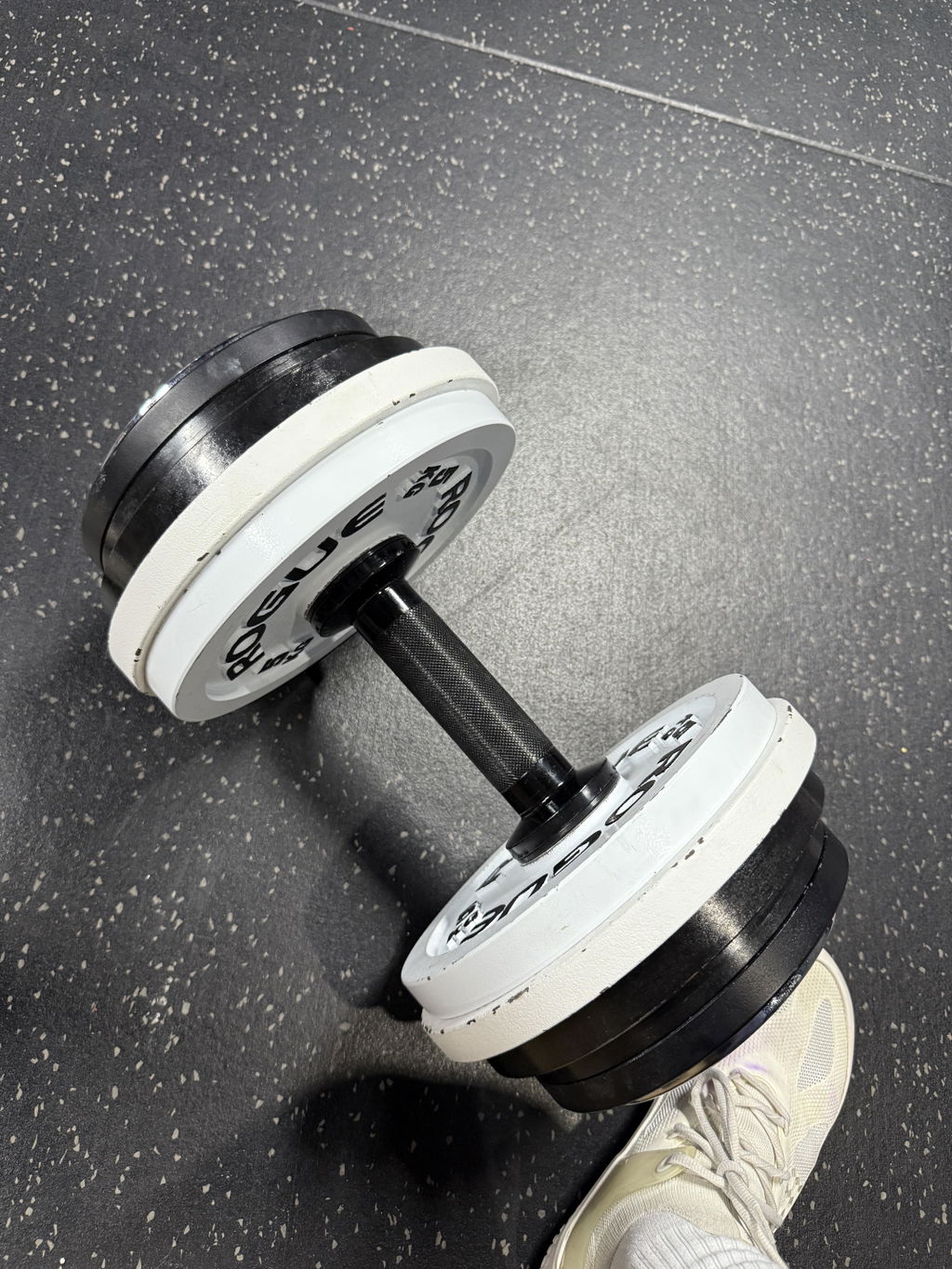 Adjustable dumbbell loaded with white plates on a gym floor