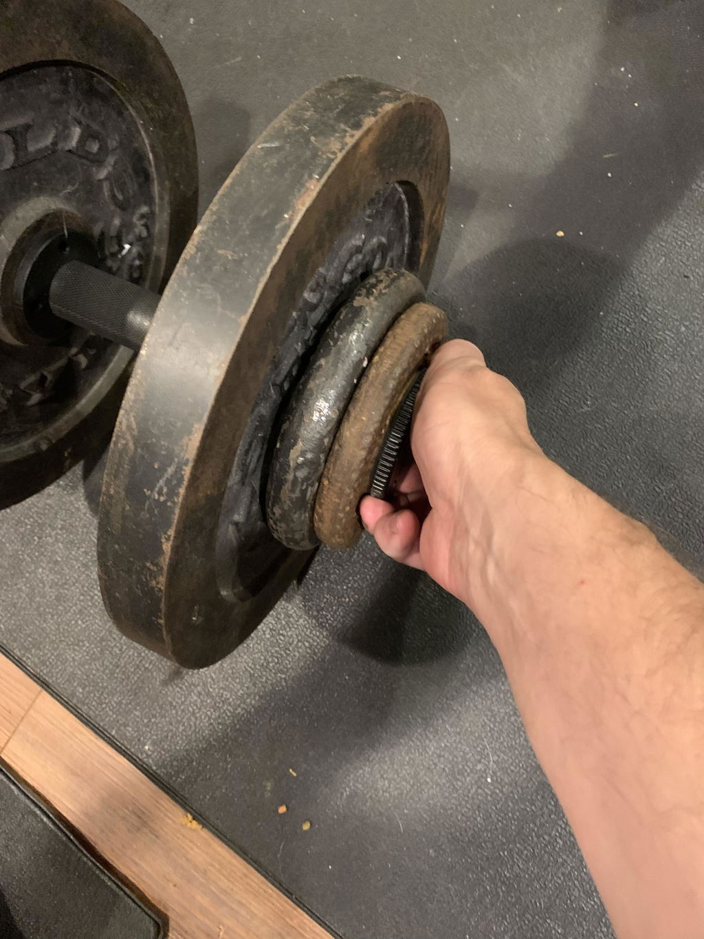 Hand lifting an adjustable handle loaded with worn iron plates