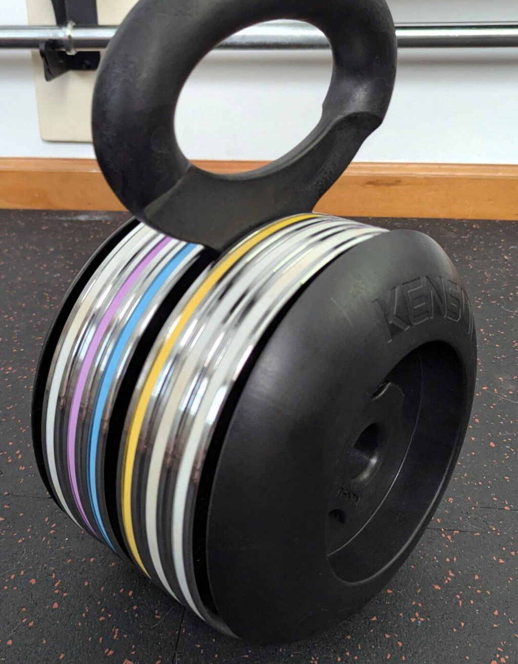 An EZ-BELL loaded with a stack of thin steel plates on a home gym floor