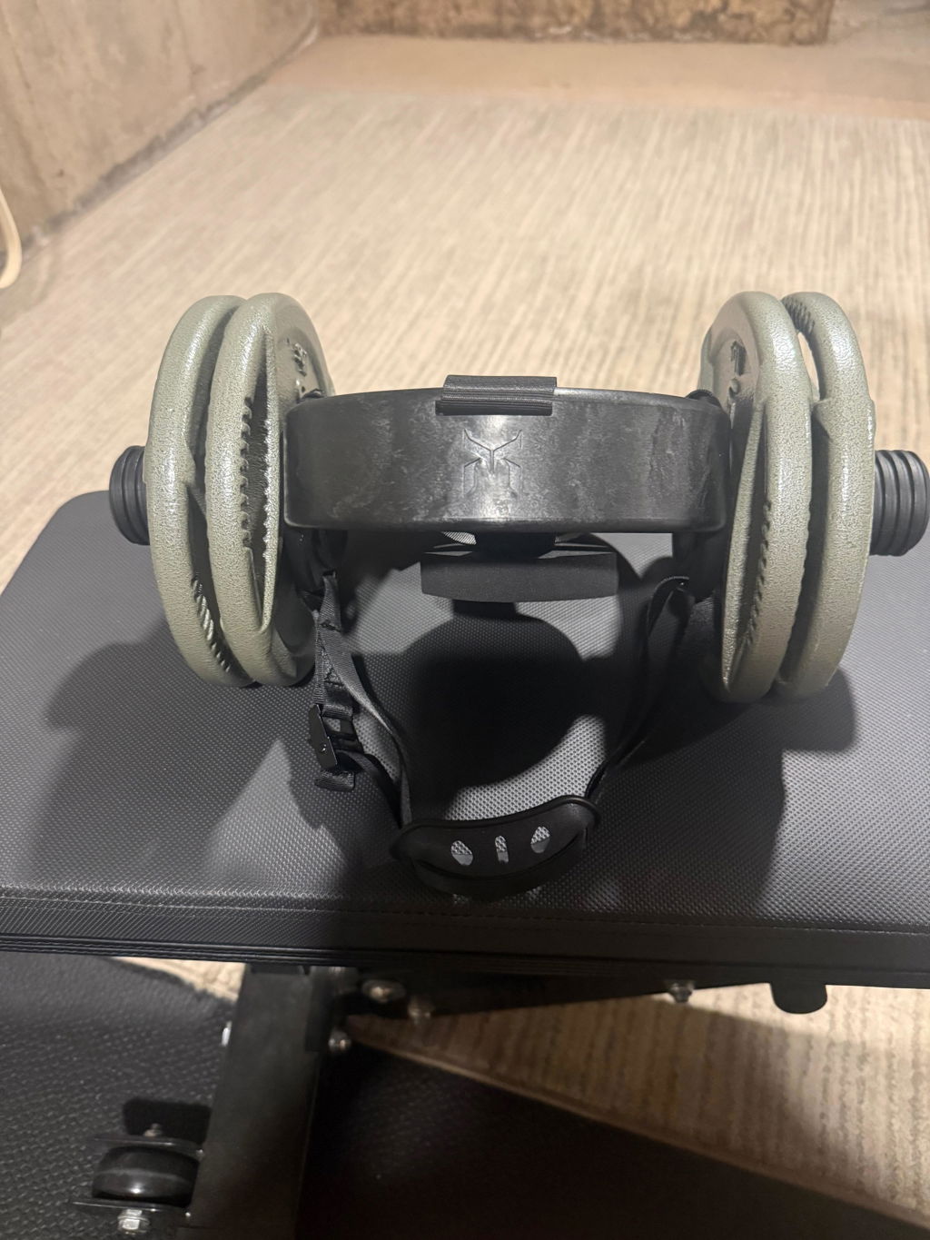 An EZ-HELM loaded with two grey plates sitting on a bench in a home gym