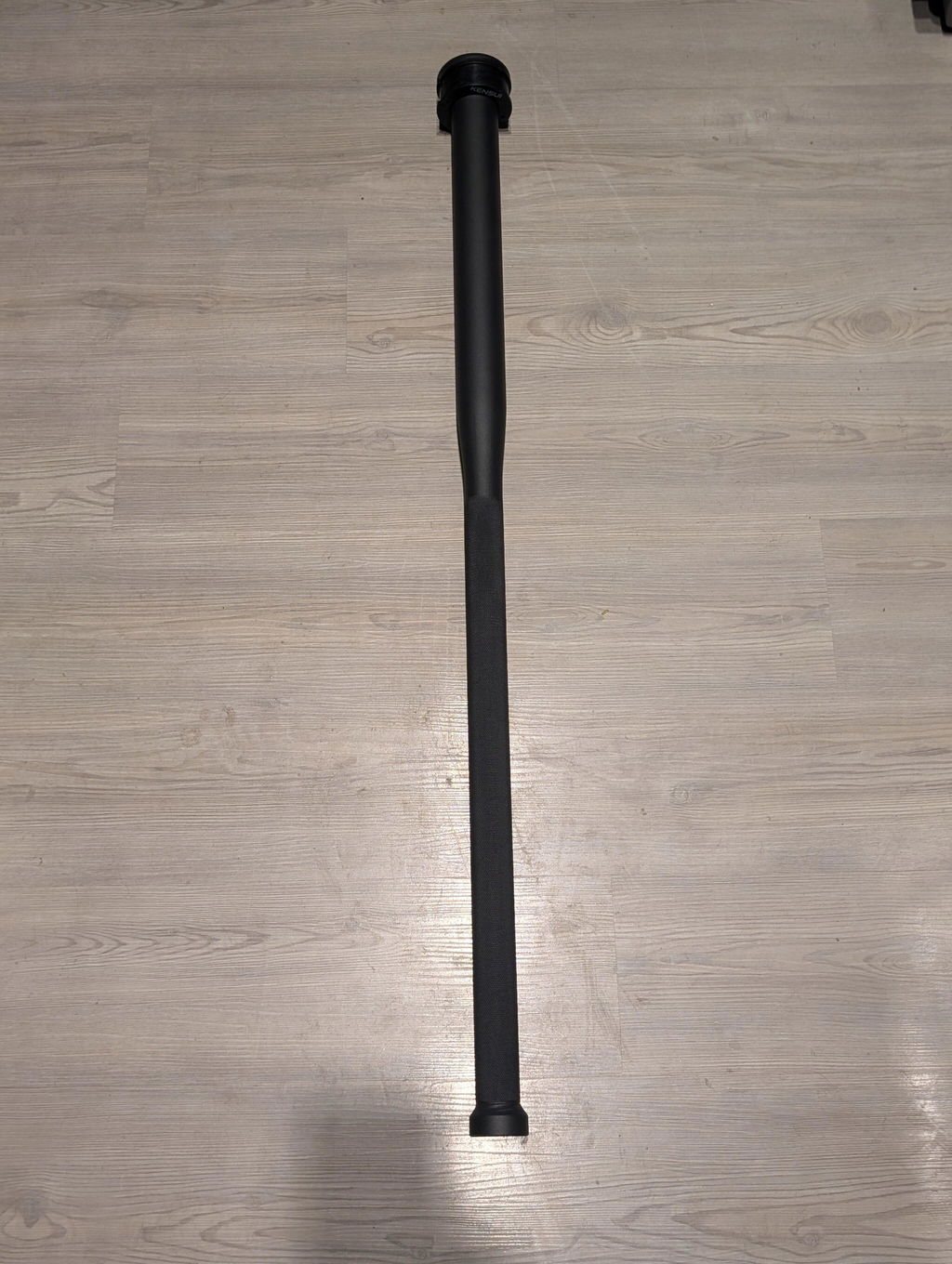 An owner's black steel mace lying unloaded on a light wooden floor at home