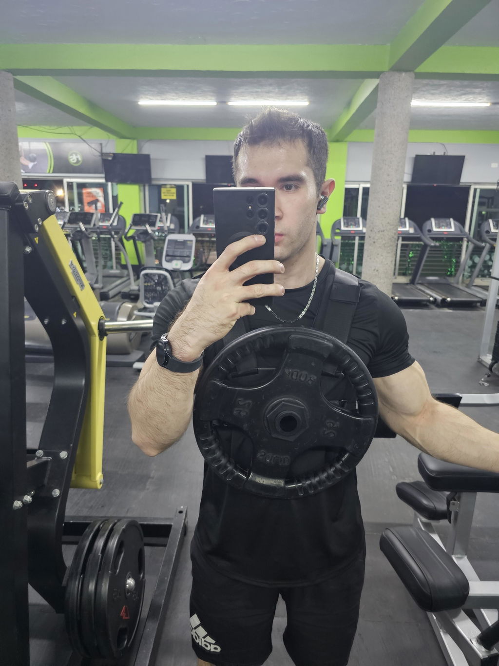 Gym mirror photo of a loaded weight vest worn over a training shirt