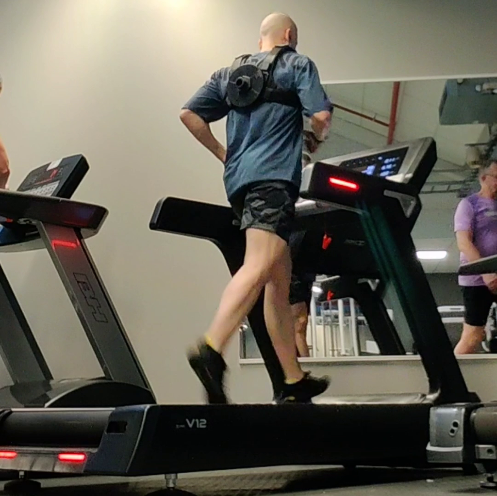 Lifter walking on a treadmill wearing a loaded weight vest