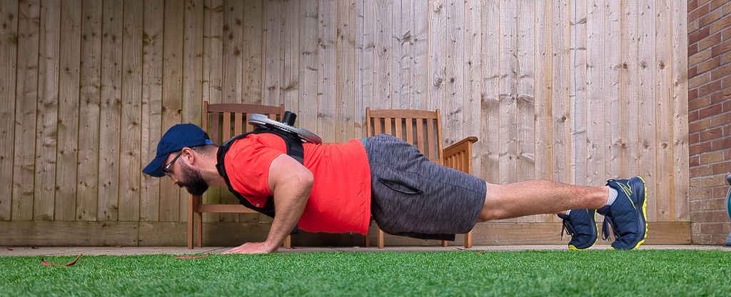 Push-up performed on grass in a loaded weight vest