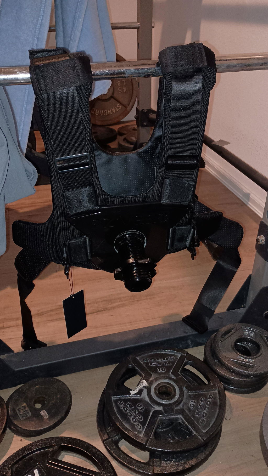 Weight vest laid on a home gym floor beside a pile of loose plates