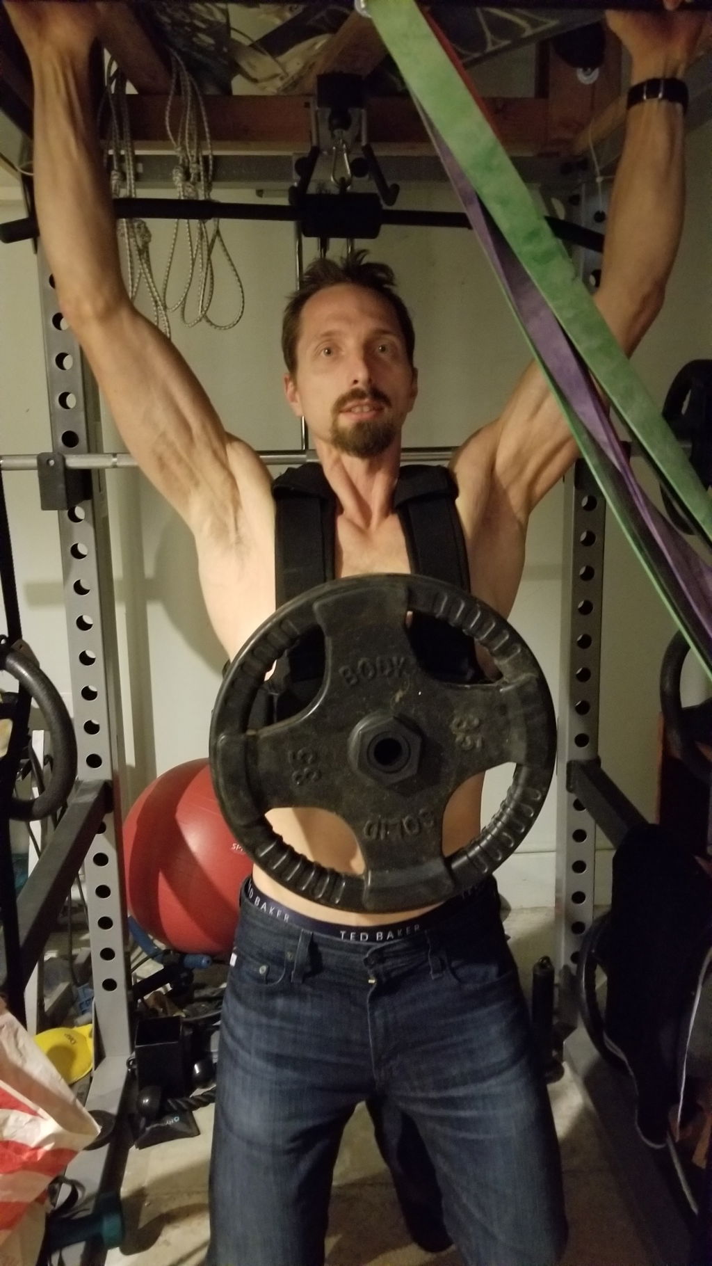 Overhead press in a garage gym while wearing a loaded vest