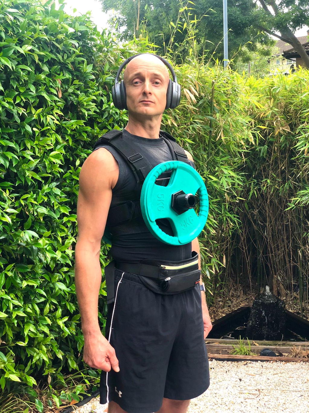 Weight vest loaded with a teal plate, worn outdoors