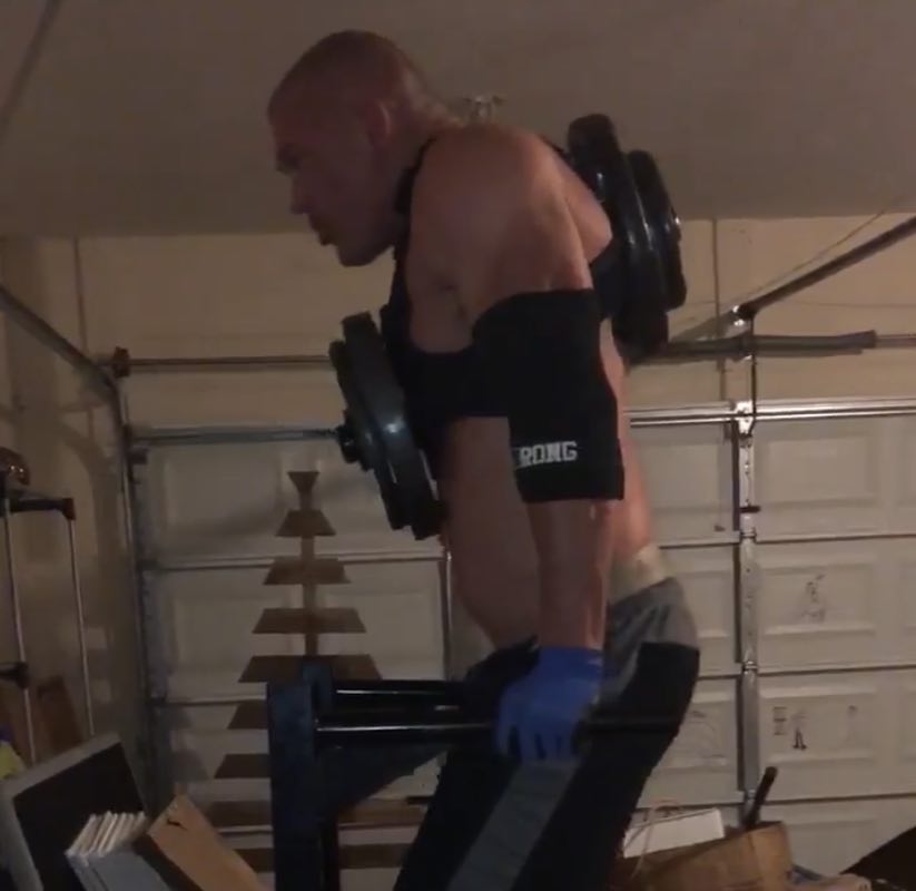 Lifter training in a garage gym wearing a loaded vest