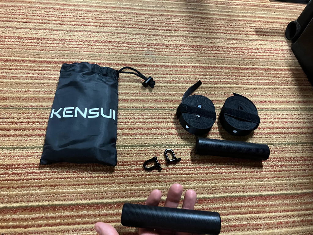 Suspension trainer parts and carry bag laid out on a floor