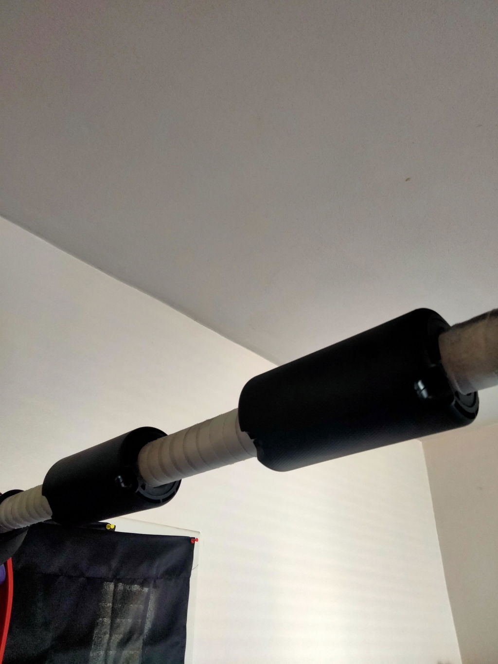 An owner's pull-up bar at home with two black thick grips of different sizes clipped on
