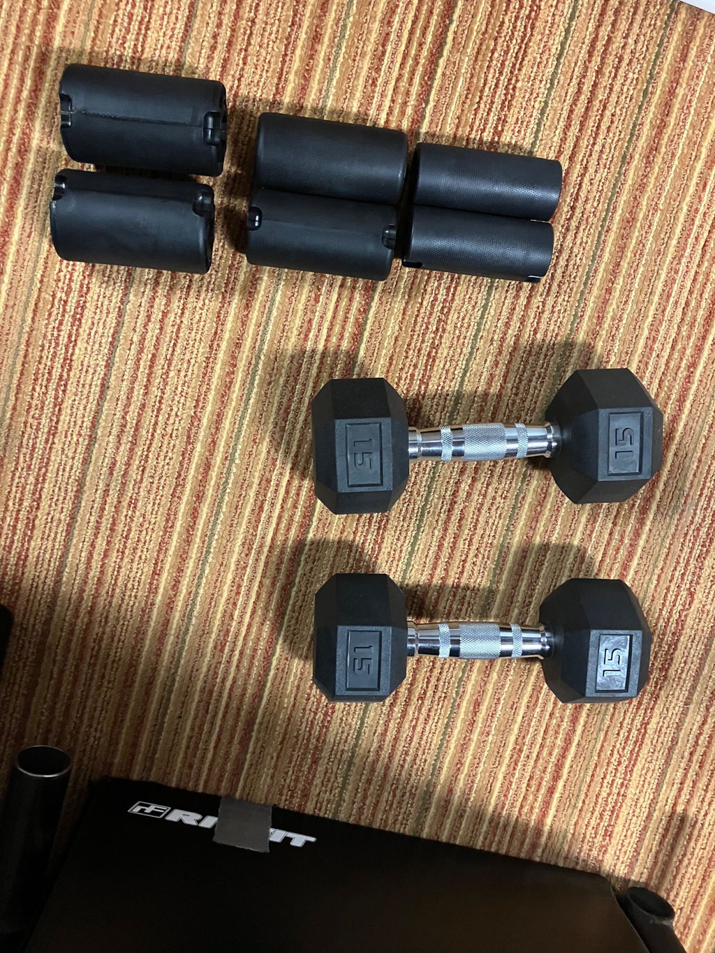 An owner's three pairs of black thick grips laid out on a carpet above two hex dumbbells