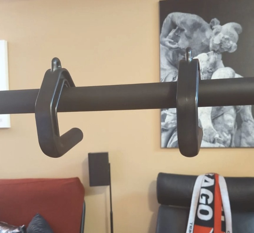 A pair of Swissies handles hooked over a wide wall-mounted pull-up bar in a home gym