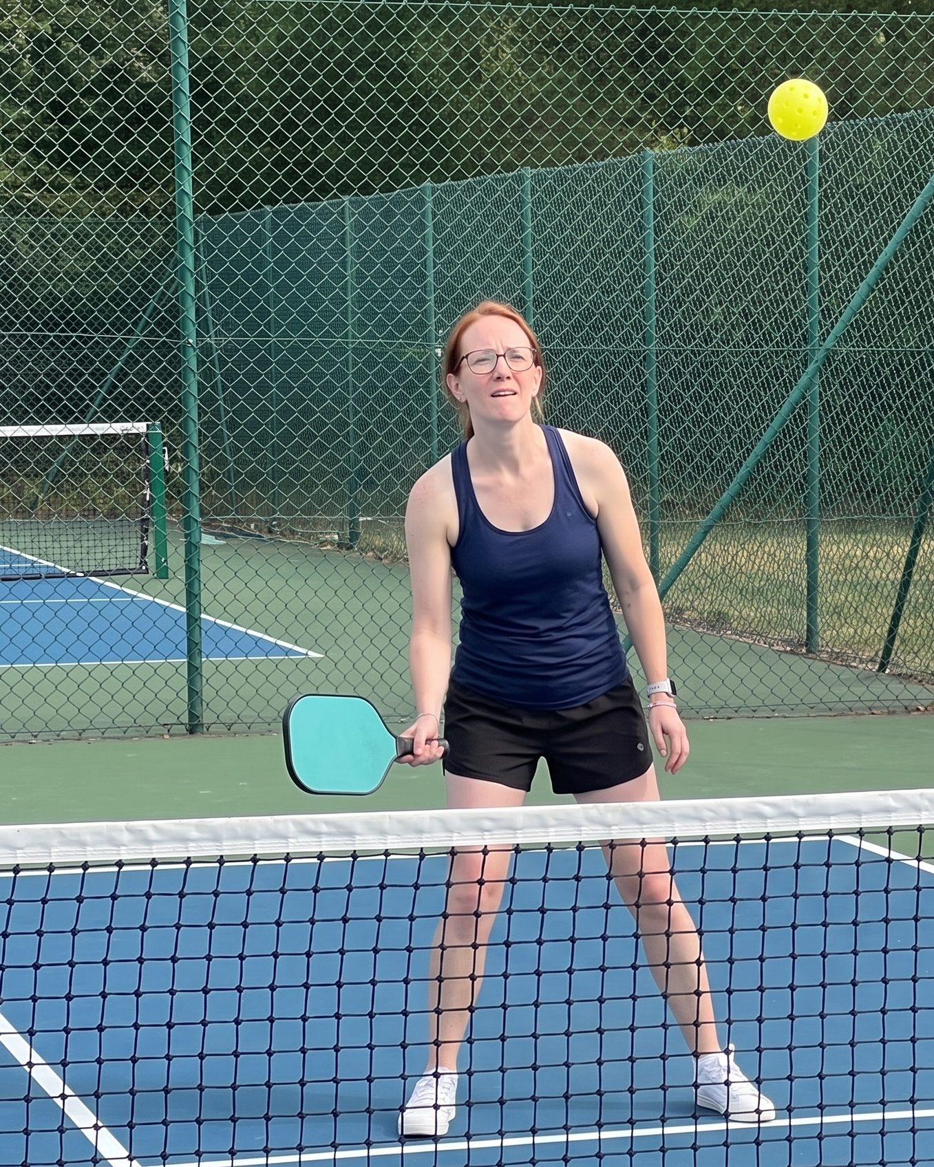 A woman at the kitchen line watches the ball she just hit float high over the net