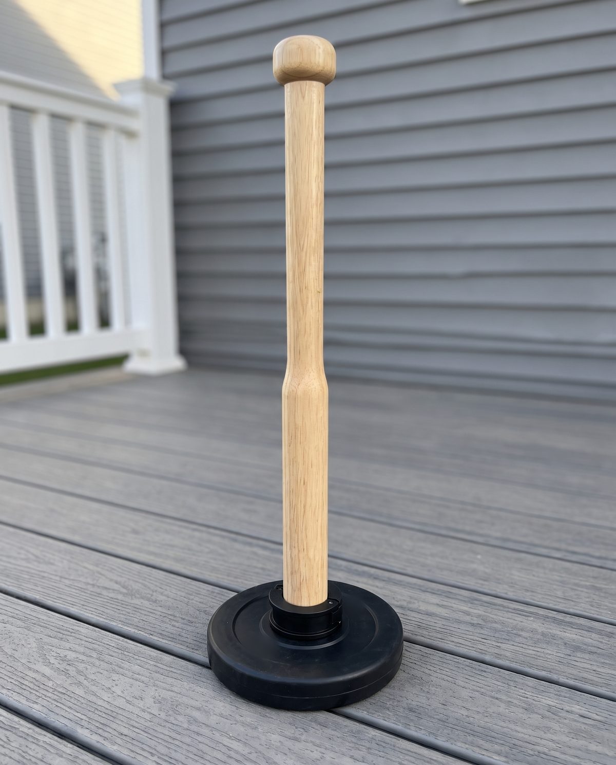 A wooden plate loaded club standing upright on a black plate on porch boards