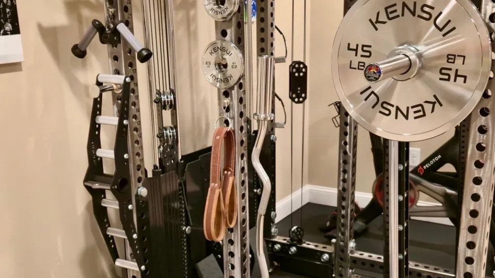 A Kensui calibrated chrome 45 pound plate loaded on a barbell in a power rack in a home gym