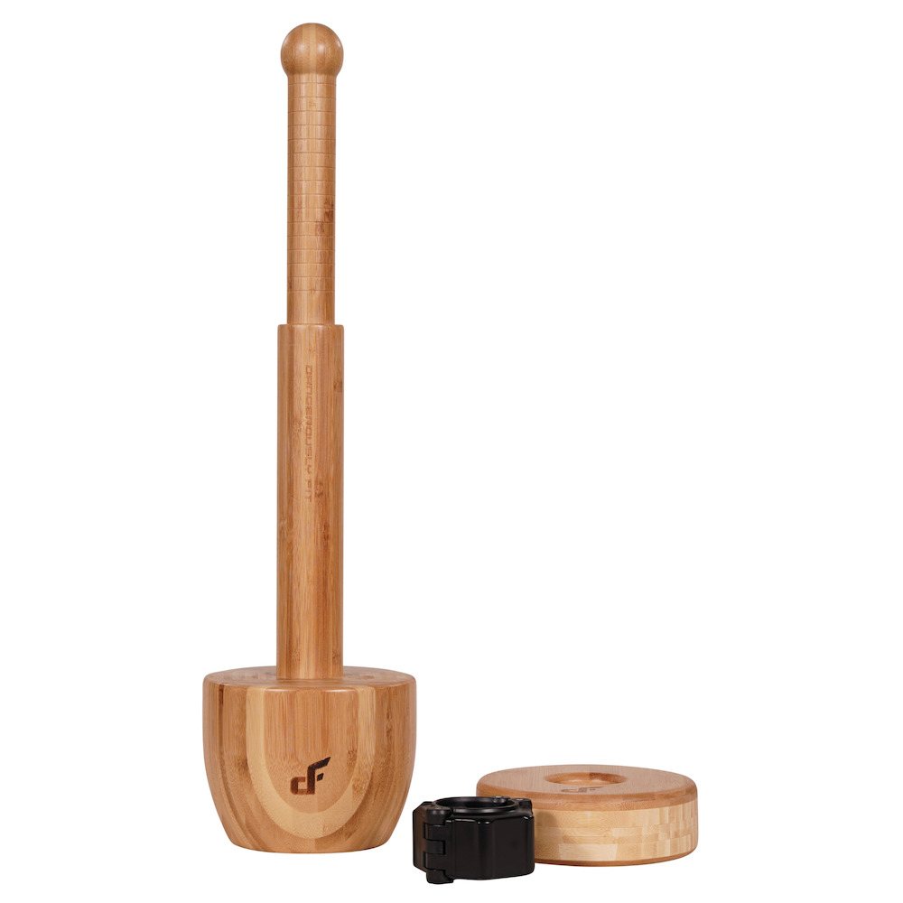 A bamboo plate-loaded club standing upright on a round wooden base next to a weight plate and a black jaw-lock collar