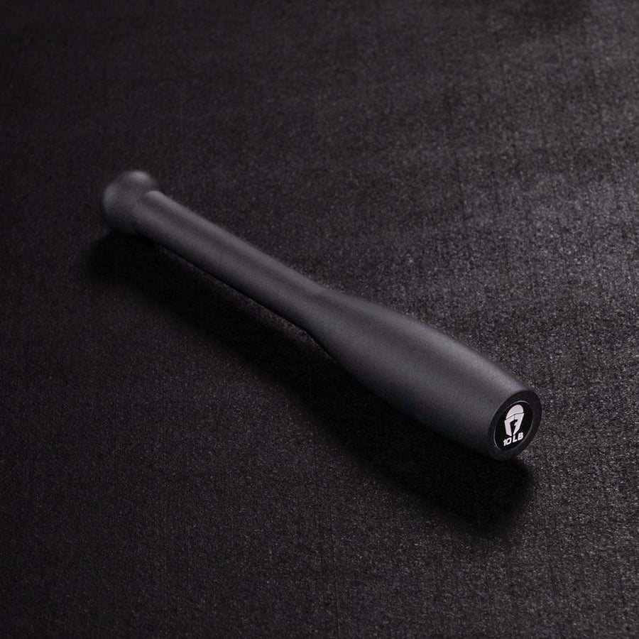 A single black one-piece steel club lying on its side on a dark surface