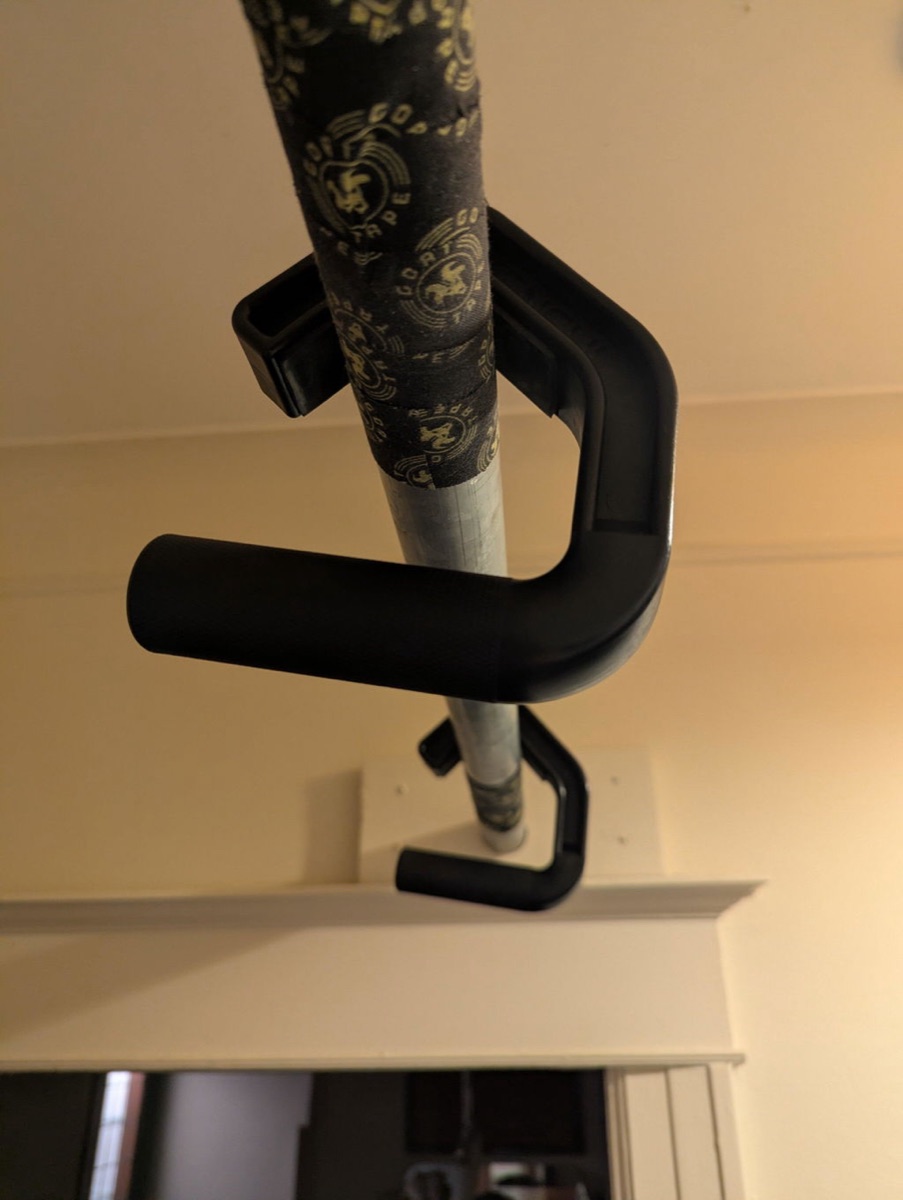 A pair of Kensui Swissies V2 handles hooked over a taped steel pull-up bar mounted in a home doorway.